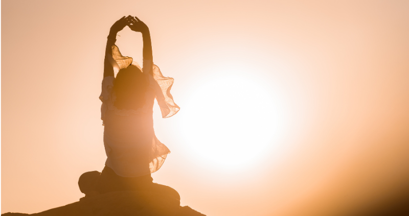 Woman stretching on top of hill at sunrise starting spiritual journey